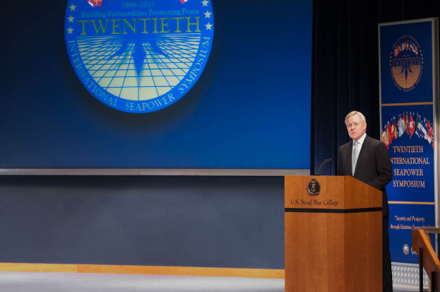 US-Außenminister Mike Pompeo, in einem schwarzen Blazer, weißem Hemd und schwarzer Krawatte, steht an einem Podium mit zwei Mikrofonen, spricht bei der 20. Internationalen Seemachtkonferenz und hat eine blaue Leinwand hinter sich sowie ein Geländer rechts vom Podium.