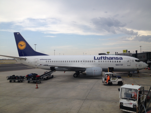 Lufthansa Airbus A320-200 am Frankfurter Airport mit Boden Service Fahrzeugen, Wagen, Verkehrskegeln, Schildern und einer bewölkten Himmel.