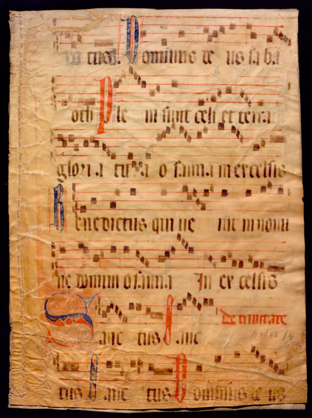 Ein illuminiertes Manuskript mit Musiknotation auf einem Blatt Papier vor einem dunklen Hintergrund, gefüllt mit Text und Musiksymbolen.