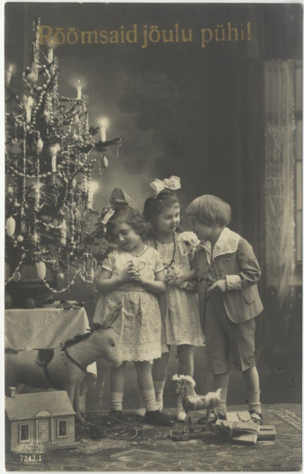 Drei Kinder in vintage-Kleidung stehen vor einem geschmückten Weihnachtsbaum mit Lichtern und Schmuck, einem drapierten Tisch links daneben und verstreuten Spielzeugen auf dem Boden, mit festlicher Schrift oben.