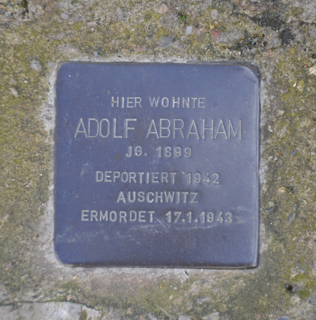Plakette mit der Aufschrift "Adolf Abraham" an einer Steinwand angebracht.