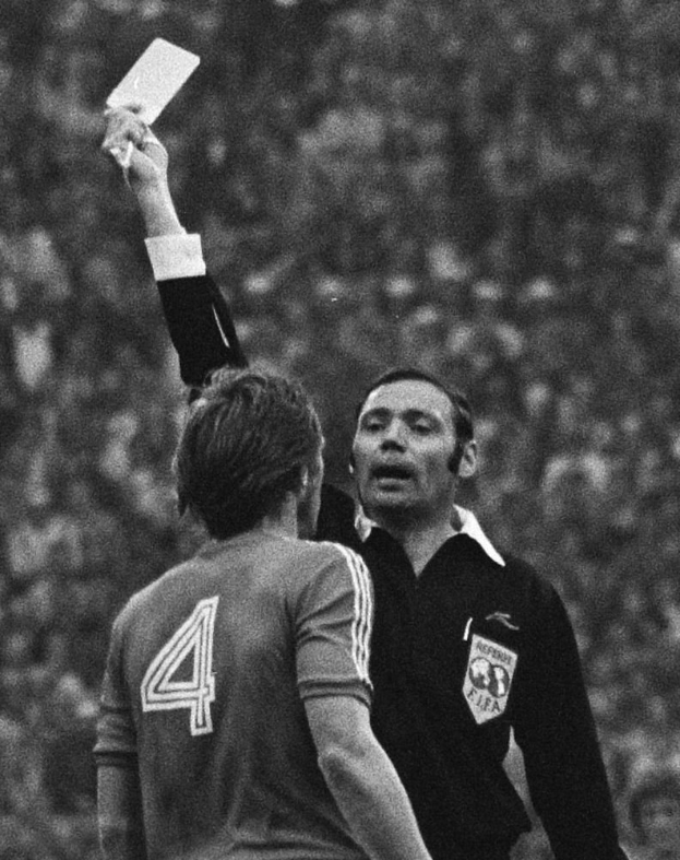 Schiedsrichter in Schwarz-Weiß-Foto hält weiße Karte hoch vor Fußballspieler