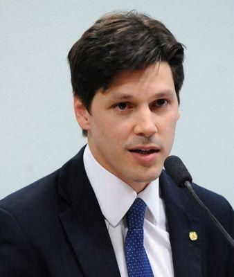 Ein Mann im Anzug und Krawatte spricht vor einer Wand in ein Mikrofon, wahrscheinlich um die Genehmigung eines Gesetzes durch die Regierung zu kommentieren.