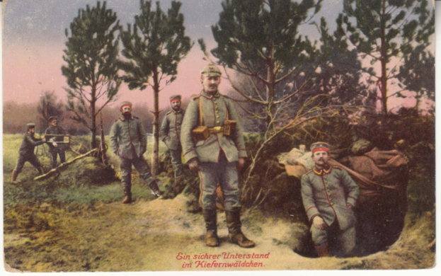 Schwarz-weiß-Postkarte einer Gruppe von Männern in militärischer Uniform, die in einem grasbewachsenen Feld mit Bäumen und einem klaren blauen Himmel im Hintergrund stehen, beschriftet mit "Deutsche Soldaten im Wald" unten.