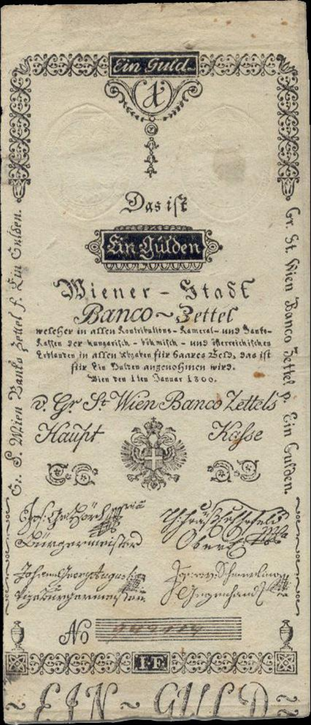 Eine alte deutsche Banknote mit schwarzem Hintergrund, die das Gesicht eines Mannes zeigt und den Text "St. Wien - Stäse Banco-Settel" trägt.