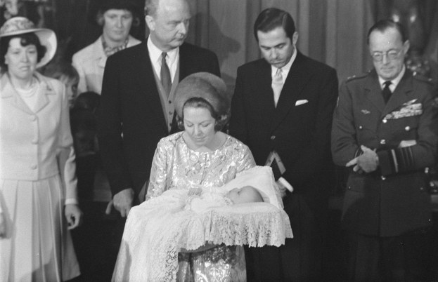 Königin Elizabeth II hält ihren neugeborenen Sohn, Prinz Philip, während Prinz Philip, Herzog von Edinburgh, neben ihnen in einem Anzug und einer Krawatte steht, mit Vorhängen im Hintergrund.