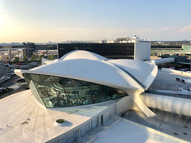 Luftaufnahme des neuen Terminalgebäudes des Los Angeles International Airport mit umgebenen Infrastruktur und Fahrzeugen bei bewölktem Himmel.