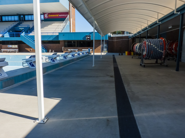 Großer Hallenbad mit zahlreichen Stühlen auf der rechten Seite, einem Gebäude im Hintergrund, verstreuten Gegenständen auf dem Boden und mehreren Pfählen auf der linken Seite, gelegen an der University of Texas at Austin.