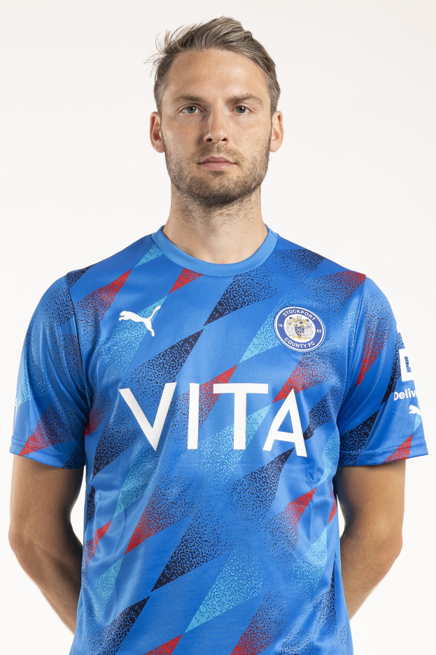 Ein Mann in einem blauen Away-Shirt von Leicester City aus der Saison 2018/19 steht vor einem weißen Hintergrund und zeigt das Team-Logo und Text auf der Vorderseite.