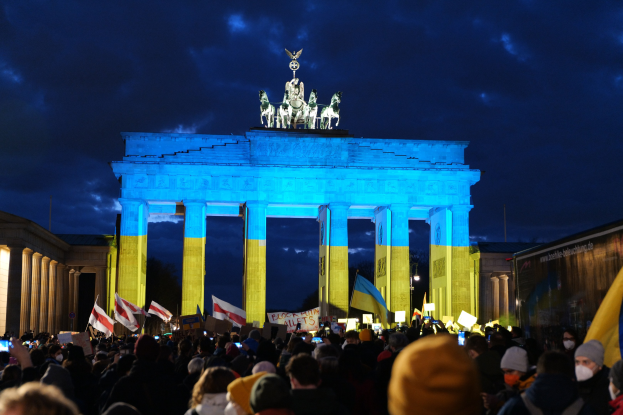 Eine Menschenmenge steht vor dem Reichstagsgebäude in Berlin, Deutschland, mit Fahnen und Schildern, mit einerBanner auf der rechten Seite.