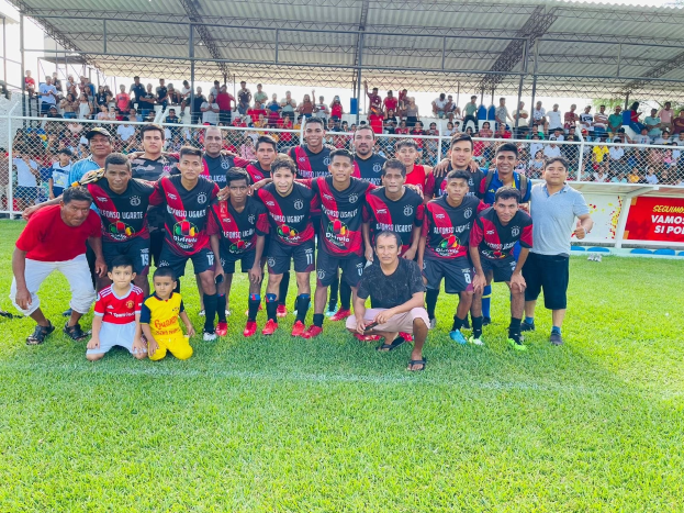 Gruppe von Männern feiert auf einem Fußballfeld mit einem Siegesschild, auf dem "Fotos Ugarte U-17 vs U-18" steht.