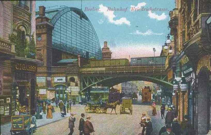 Alte Ansichtskarte einer belebten Straßenkreuzung in Berlin, Deutschland, mit Fußgängern, Kutschen, Gebäuden, Laternen, einer Brücke und einem bewölkten Himmel, mit Text oben.