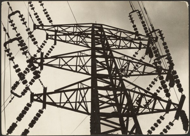 Schwarz-weiß-Foto eines Hochspannungsmasten mit Drähten vor einem Himmel-Hintergrund, mit Text unten.