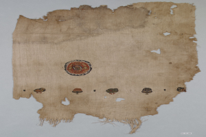 Ein Stoffstück mit einem lebendigen, detaillierten kreisförmigen Design, das verschiedene geometrische Formen und Farben gegen einen weißen Hintergrund zeigt.