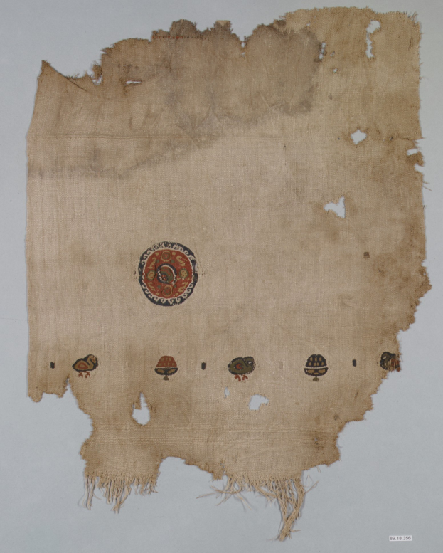 Ein Stoffstück mit einem lebendigen, detaillierten kreisförmigen Design, das verschiedene geometrische Formen und Farben gegen einen weißen Hintergrund zeigt.