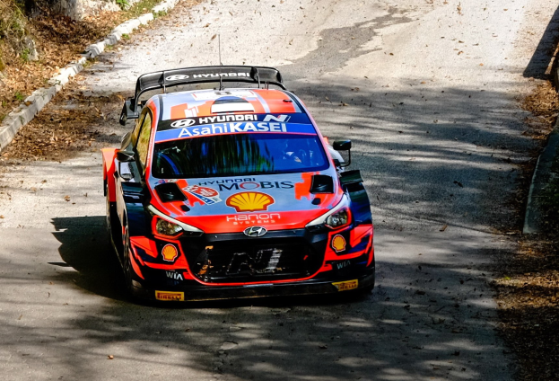 Ein Rallyeauto mit Textmarkierungen fährt auf einer bewaldeten, kurvenreichen Straße während der 2018 FIA World Rally Championship.