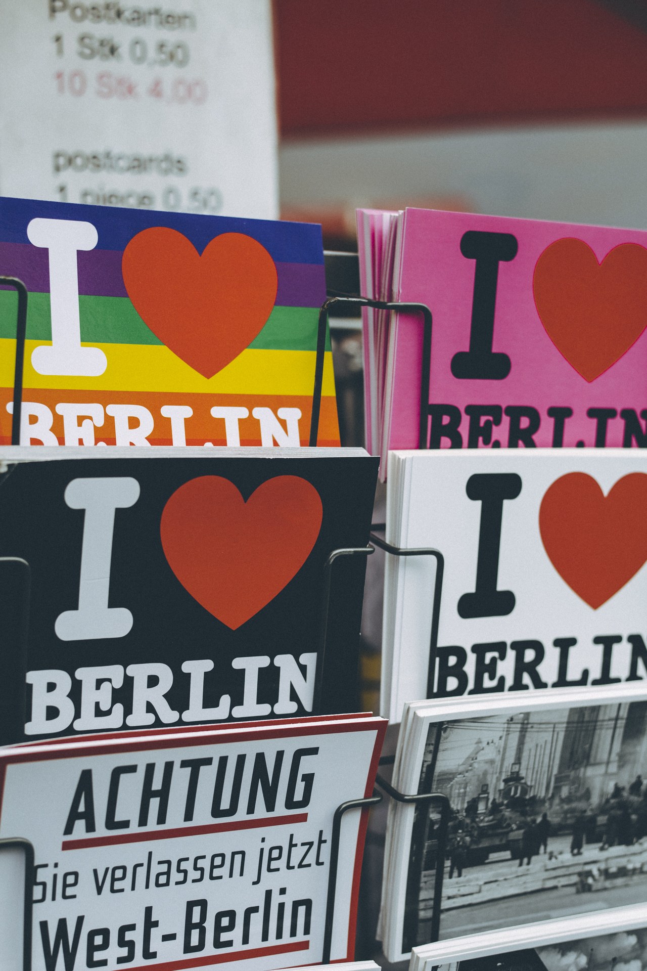 Ein Gestell mit Büchern und Postern mit der Aufschrift "Ich liebe Berlin" vor einem leicht unscharfen, verträumten Hintergrund.