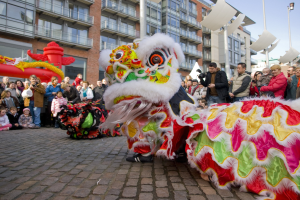 Ein lebendiges chinesisches Neujahrsfest in Amsterdam mit einer Löwen-Tanz-Show vor einem Gebäude und einem klaren blauen Himmel.