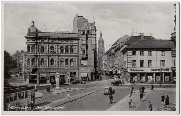 Schwarz-weiß-Foto einer belebten Münchner Stadtstraße mit Fußgängern, Fahrzeugen und Gebäuden, Bäumen im Hintergrund und Text unten.