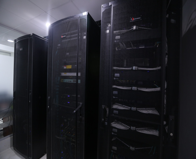 Eine Reihe von Servern in einem Rechenzentrum, mit einer Wand auf der rechten Seite und Deckenleuchten über ihnen.