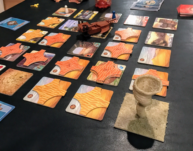 Ein unordentlicher Tisch mit Star Wars: The Old Republic-Sammelkarten, Spielzeugen und Gegenständen in einem Raum mit einer Wand im Hintergrund.