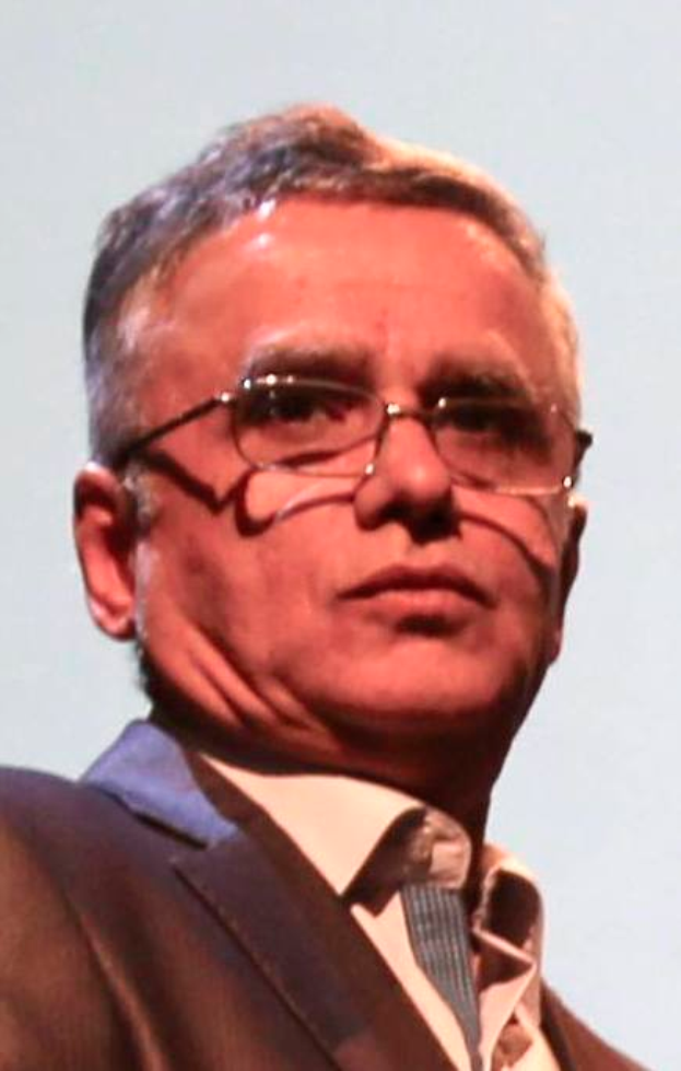 Ein Mann in einem Blazer, Krawatte und Brille steht vor einem weißen Hintergrund, identifiziert als CEO der Bank of England.